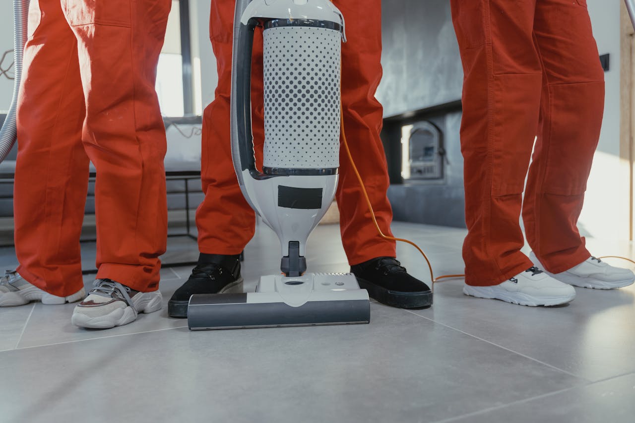 expertise-01 Team of professional cleaners in red uniforms using a vacuum cleaner indoors.